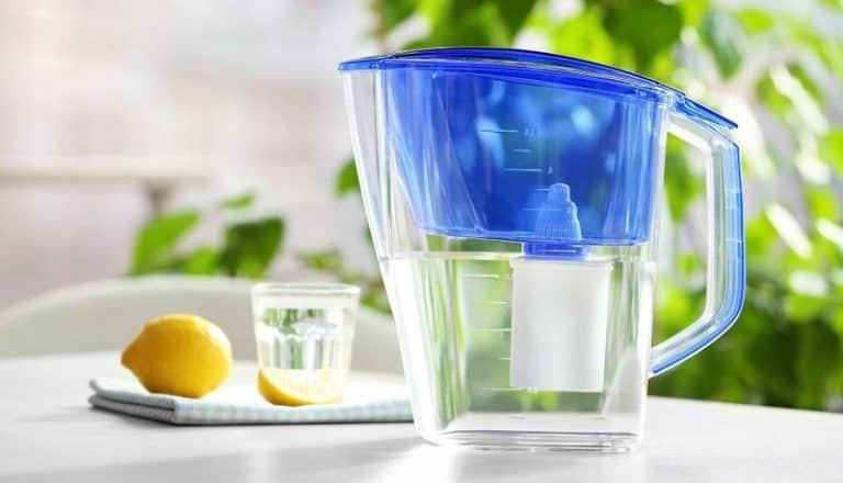 alkaline water pitcher with filter and glass sitting out on a table outdoors
