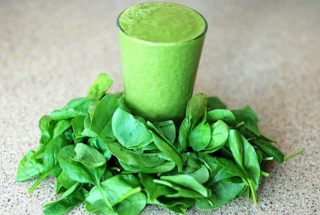 green smoothie on a bed of baby spinach leaves